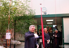 Wethouder Valstar van de gemeente Westland mocht knippen. Een deel van het gezelschap kijkt van een afstandje toe.