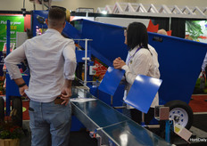 Uitleg op de stand bij Machinerie S.B. over een machine om potten met potgrond te vullen.